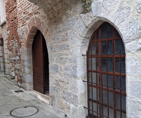 Porte en bois sous une arche de pierre, dans une ruelle du vieux Luzech