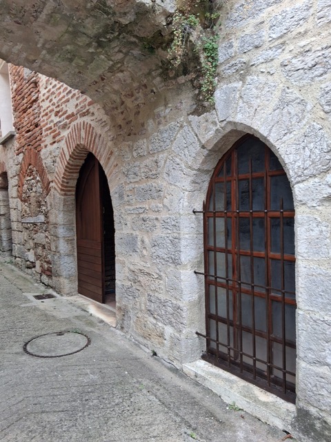 Porte en bois sous une arche de pierre, dans une ruelle du vieux Luzech