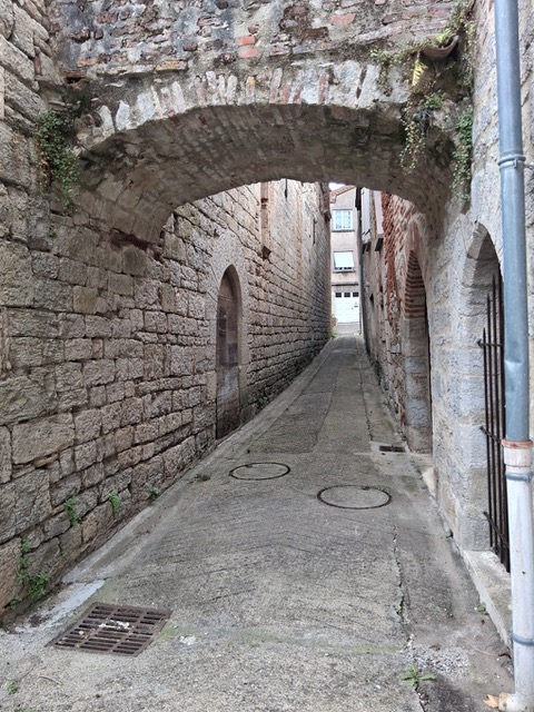 Ruelle pavée passant sous une arche de pierre dans le vieux Luzech
