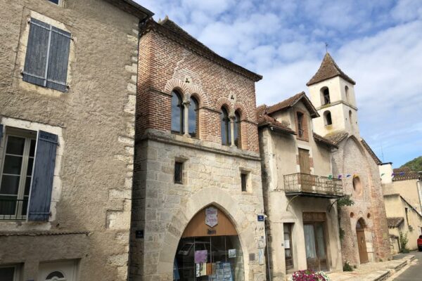 Façade médiévale en briques de la Maison des Consuls et clocher, dans une rue de Luzech